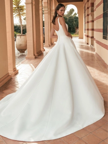 Blue by Enzoani Ulandra is a luxury satin ballgown wedding dress featuring a clean structured bodice, elegant scoop neckline, wide shoulder straps and a sweeping cathedral-length train. Designed for modern brides seeking a minimalist designer wedding gown
