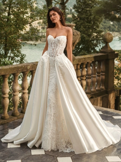 Bride wearing the Enzoani WANDA wedding dress, a romantic strapless lace fit-and-flare bridal gown with an illusion corset bodice and detachable satin overskirt, perfect for luxury, modern, and destination weddings.