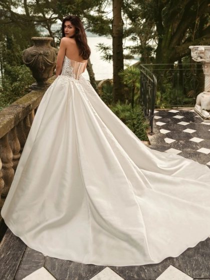 Bride wearing the Enzoani WANDA wedding dress, a romantic strapless lace fit-and-flare bridal gown with an illusion corset bodice and detachable satin overskirt, perfect for luxury, modern, and destination weddings.