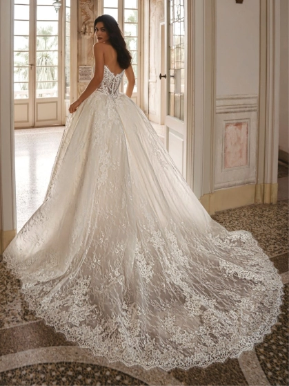 Enzoani Waylen luxury wedding dress with a strapless sweetheart neckline, intricately embroidered floral lace corset bodice, voluminous ball gown skirt, couture detailing, and dramatic cathedral train. Designer bridal gown by Enzoani combining modern roman