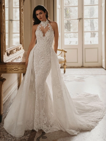 Enzoani Wednesday luxury wedding dress with a fitted mermaid silhouette, illusion halter neckline, floral lace embroidery, sculpted corset bodice, detachable overskirt, and dramatic cathedral train. Couture bridal gown by Enzoani combining modern glamour,